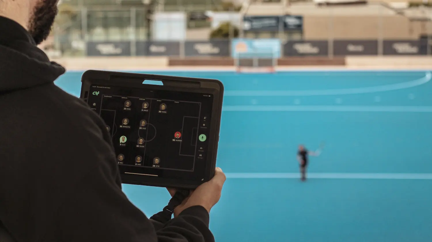 Coach holding the Coach App while training with players using the Coachwhisperer from the distance